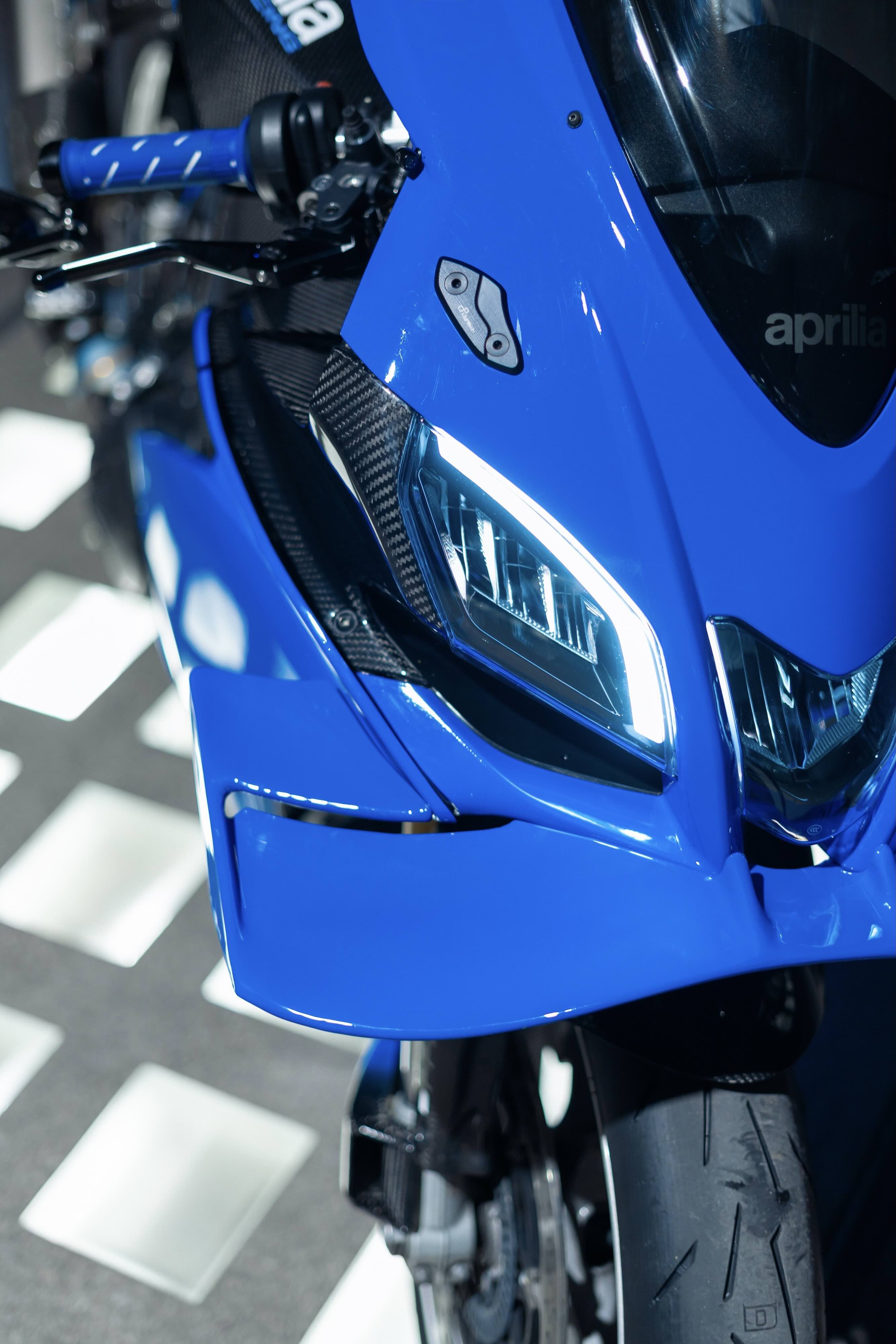 Close-up of a blue motorcycle with visible branding on a blurred background
